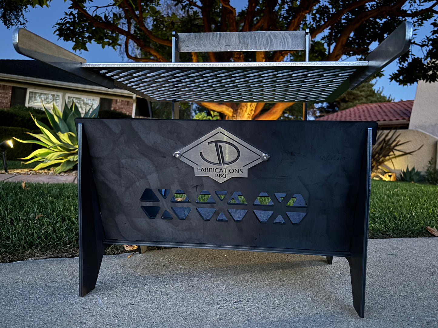 JD Fabrications Laser Cut grill with Stainless Steel grate on patio with plants in background 