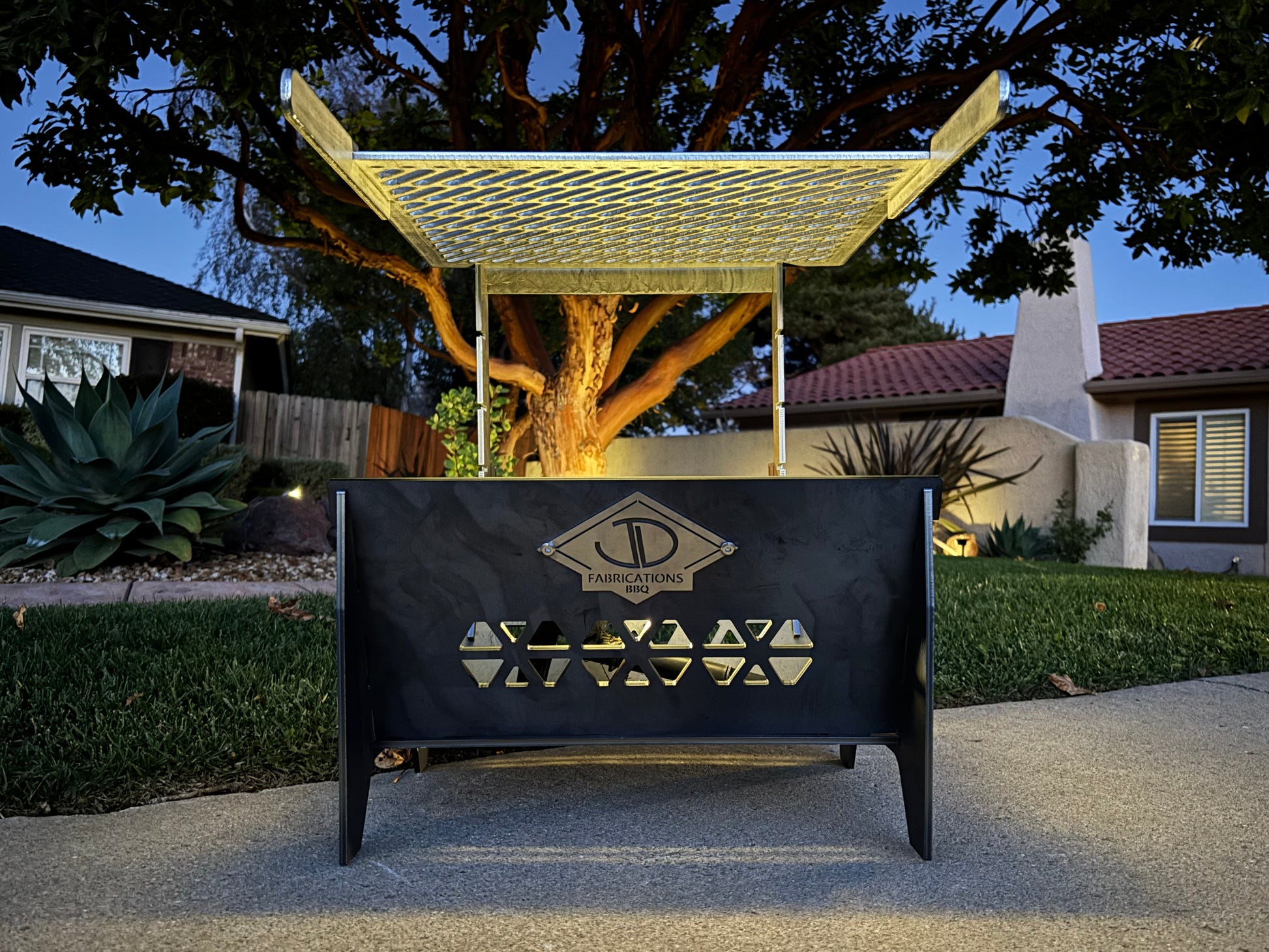 Outdoor fire pit with laser cut adjustable grate in a backyard setting