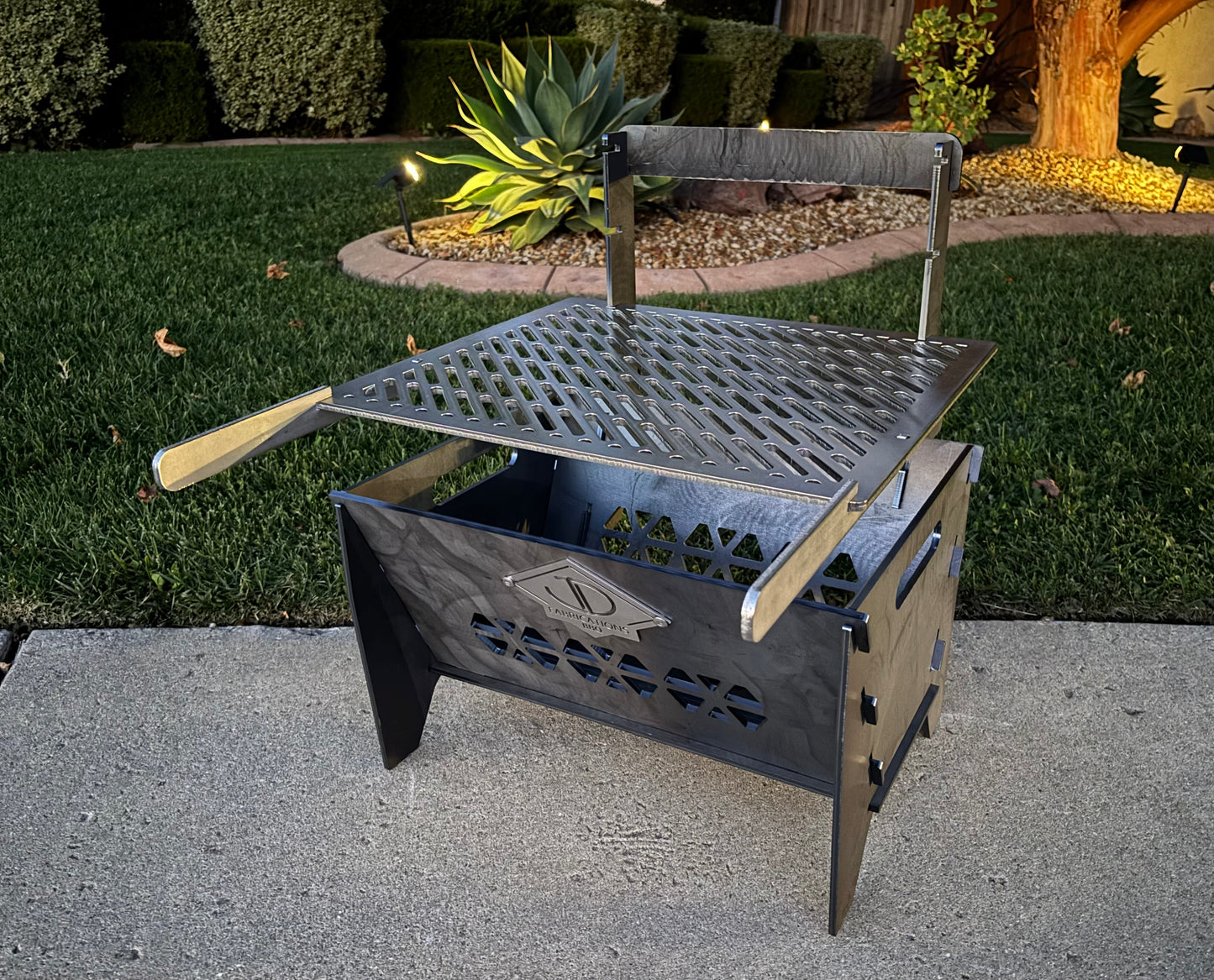 Portable laser cut grill with height adjustable laser cut grill grate in patio setting with plants in background 